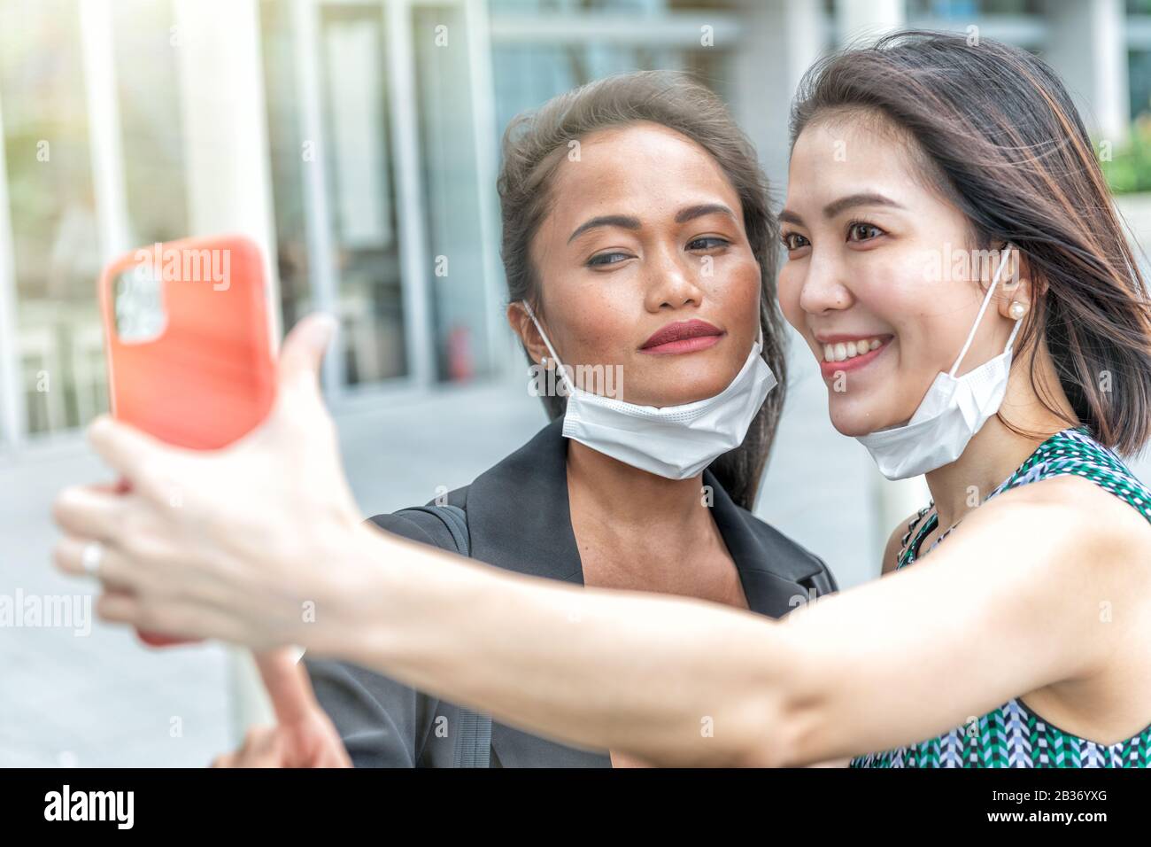 Couple of asian female friends enjoying outdoor time together wearing hygienic mask to prevent the virus PM2.5 and Coronavirus. Air pollution, Environ Stock Photo
