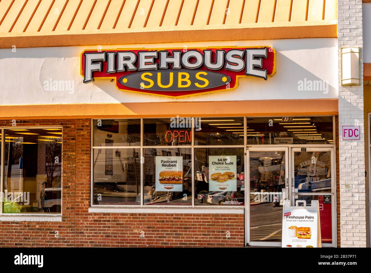 Horizontal medium closeup of 'Firehouse Subs' fast food sandwich shop showing brand and logo on facade of building above windows and entrance. Stock Photo