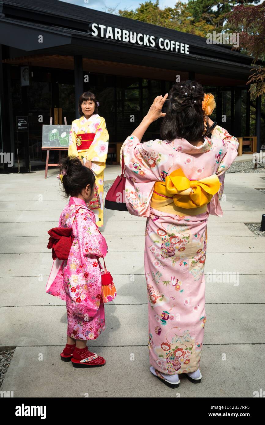 Seemingly three generations of women wearing kimono (which can be hired for the day) by a Starbucks near the grounds of Byodo-in, a temple in Uji Stock Photo