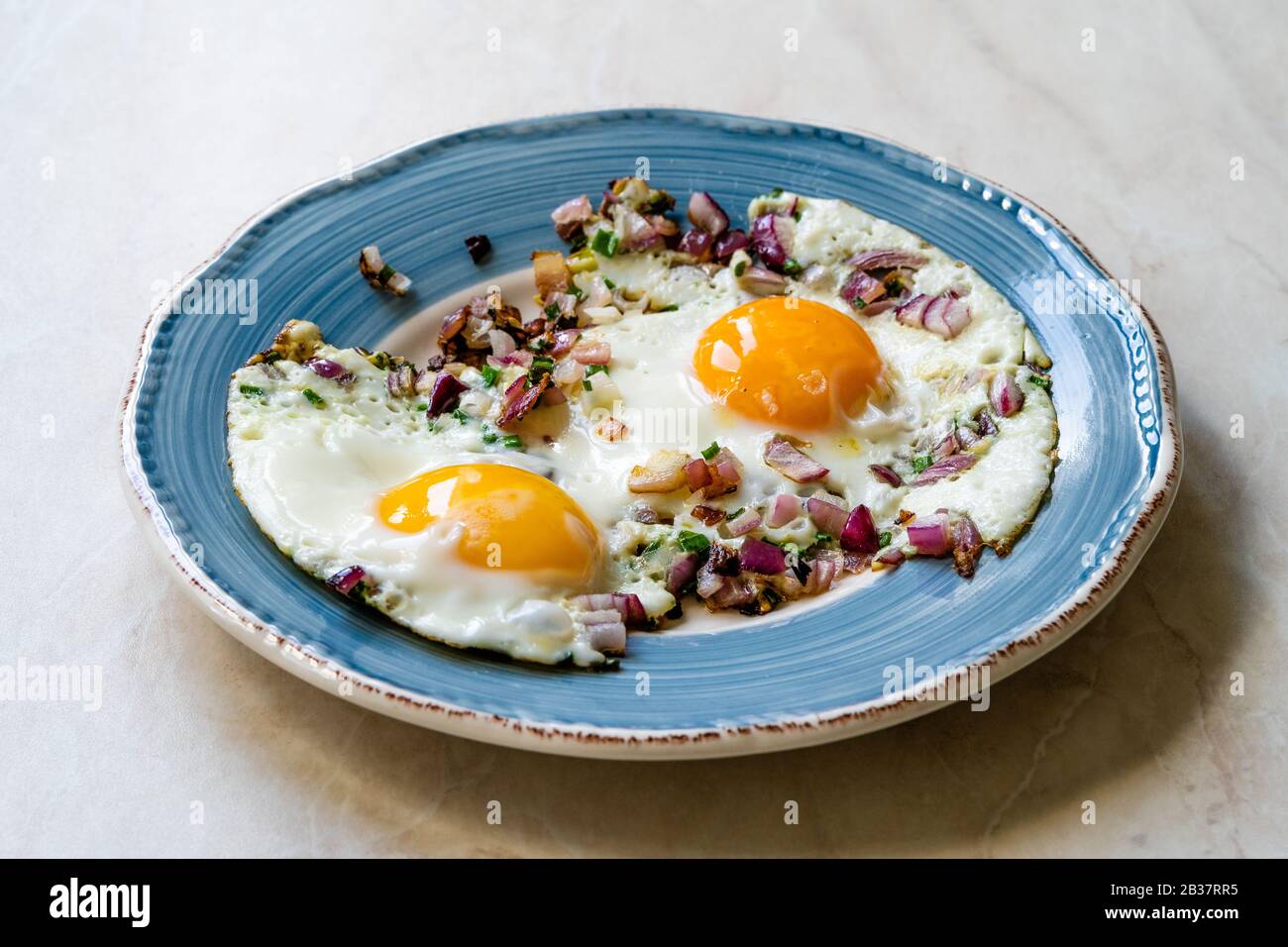Sunny Side Up Fried Eggs with Red Onions and Chives for Breakfast in Plate. Organic Food. Stock Photo