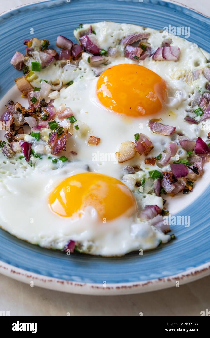 Sunny Side Up Fried Eggs with Red Onions and Chives for Breakfast in Plate. Organic Food. Stock Photo