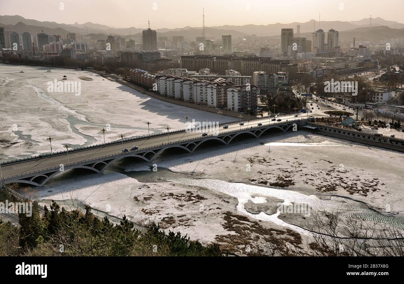 Aerial view of the bridge, frozen river and Chengde city downtown, Hebei province (China), in winter. Stock Photo