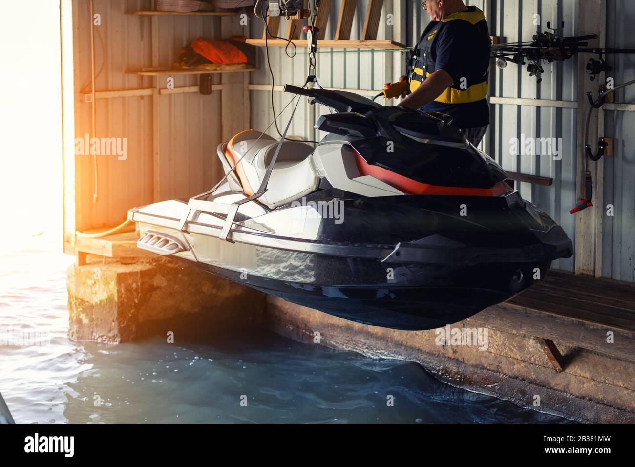 Senior Man Launching Or Lifting Modern Fast Jetski Hanged On