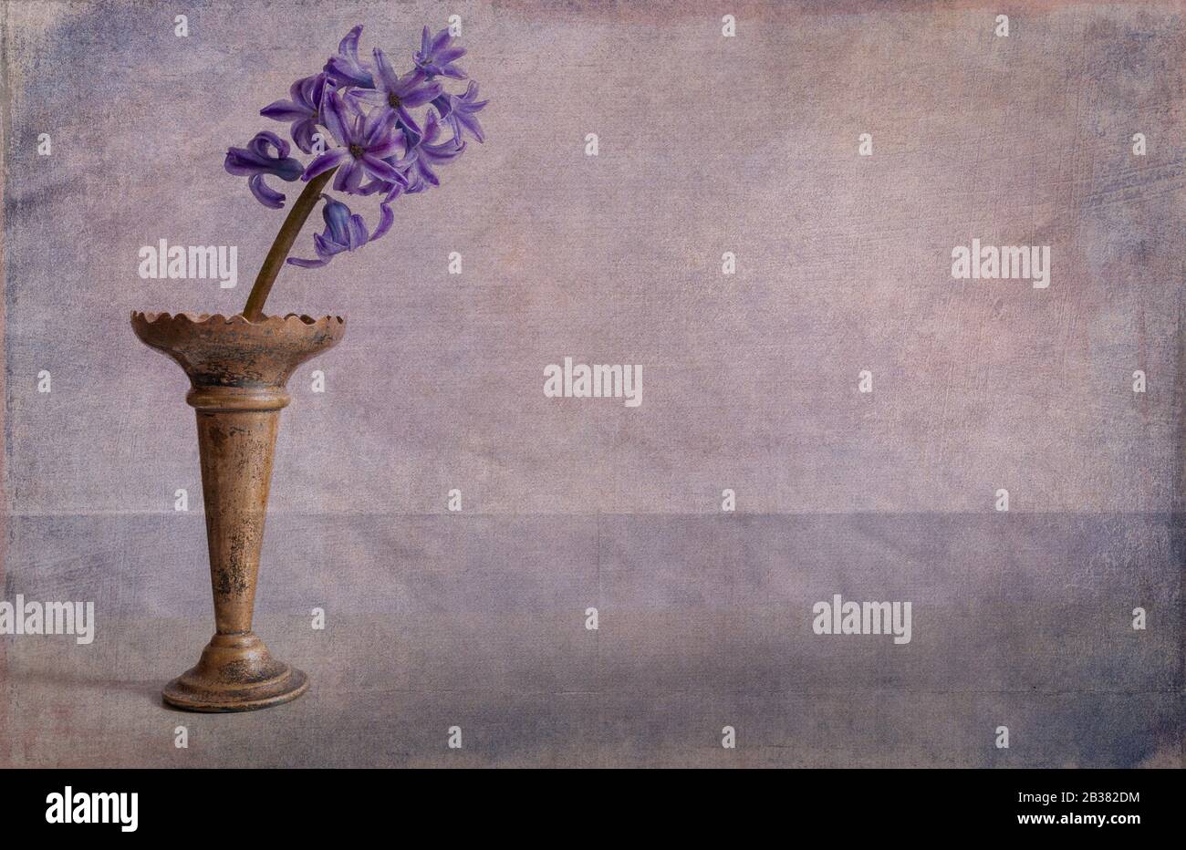single Bluebell  in old metal vase textured painterly  minimalist image with room for text, concept spring. Stock Photo