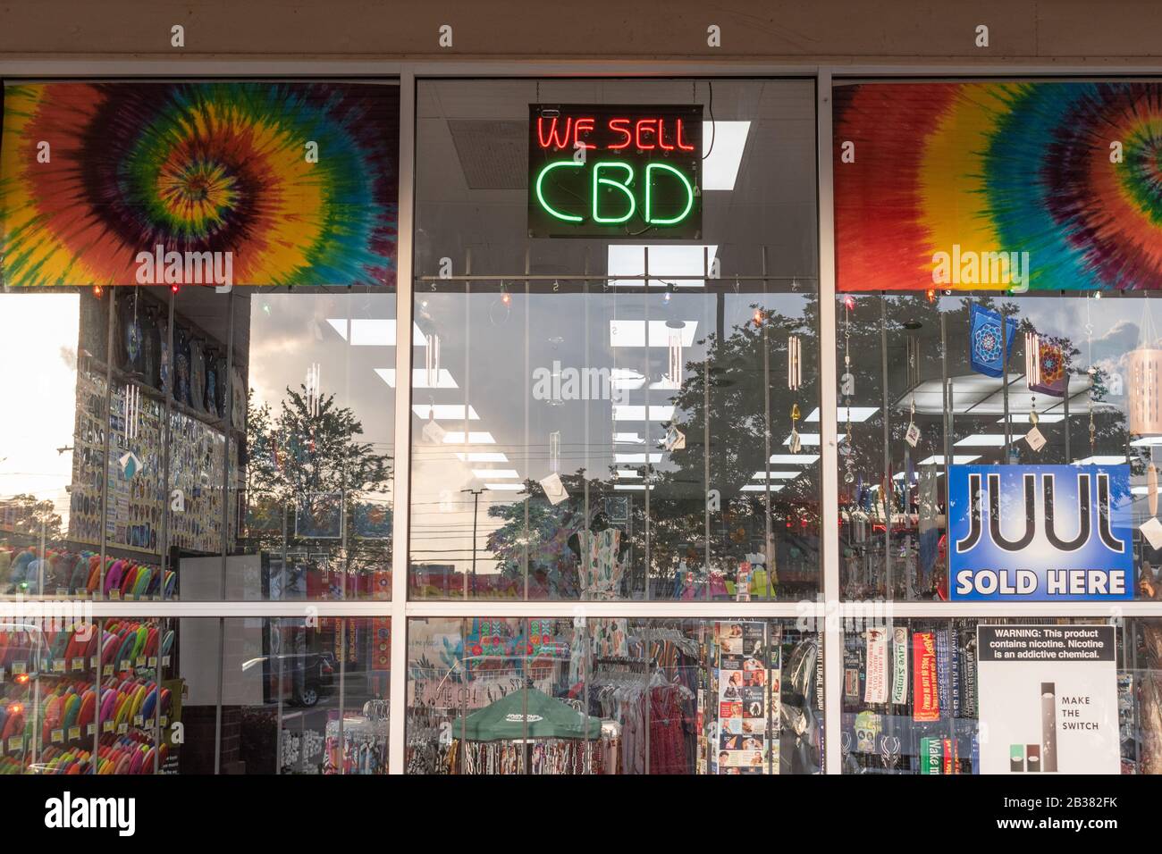 Charlotte, NC/USA - May 10, 2019: Medium closeup of colorful reflective storefront window with ads for CBD oil and JUUL e-cigarettes. Stock Photo