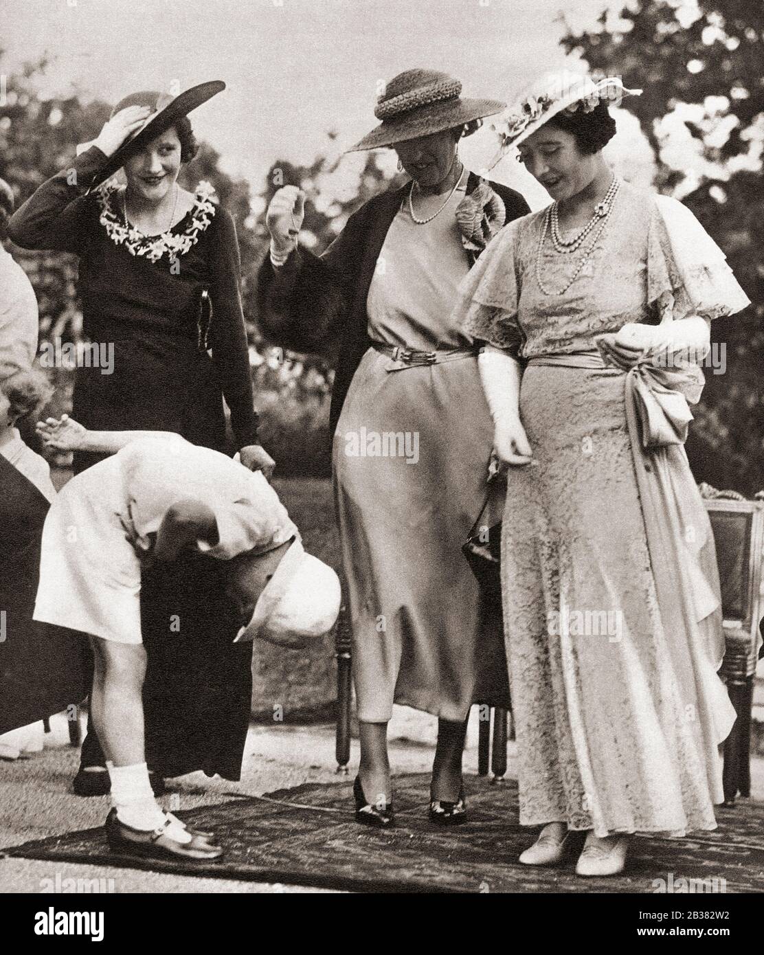A young boy bowing to Elizabeth, Duchess of York, future Queen Elizabeth, at a Child Welfare garden party, St. James's Palace, he unfortunately forgot to remove his hat.  Queen Elizabeth, The Queen Mother.  Elizabeth Angela Marguerite Bowes-Lyon, 1900 – 2002.  Wife of King George VI and mother of Queen Elizabeth II. From The Coronation Souvenir Book, published 1937. Stock Photo