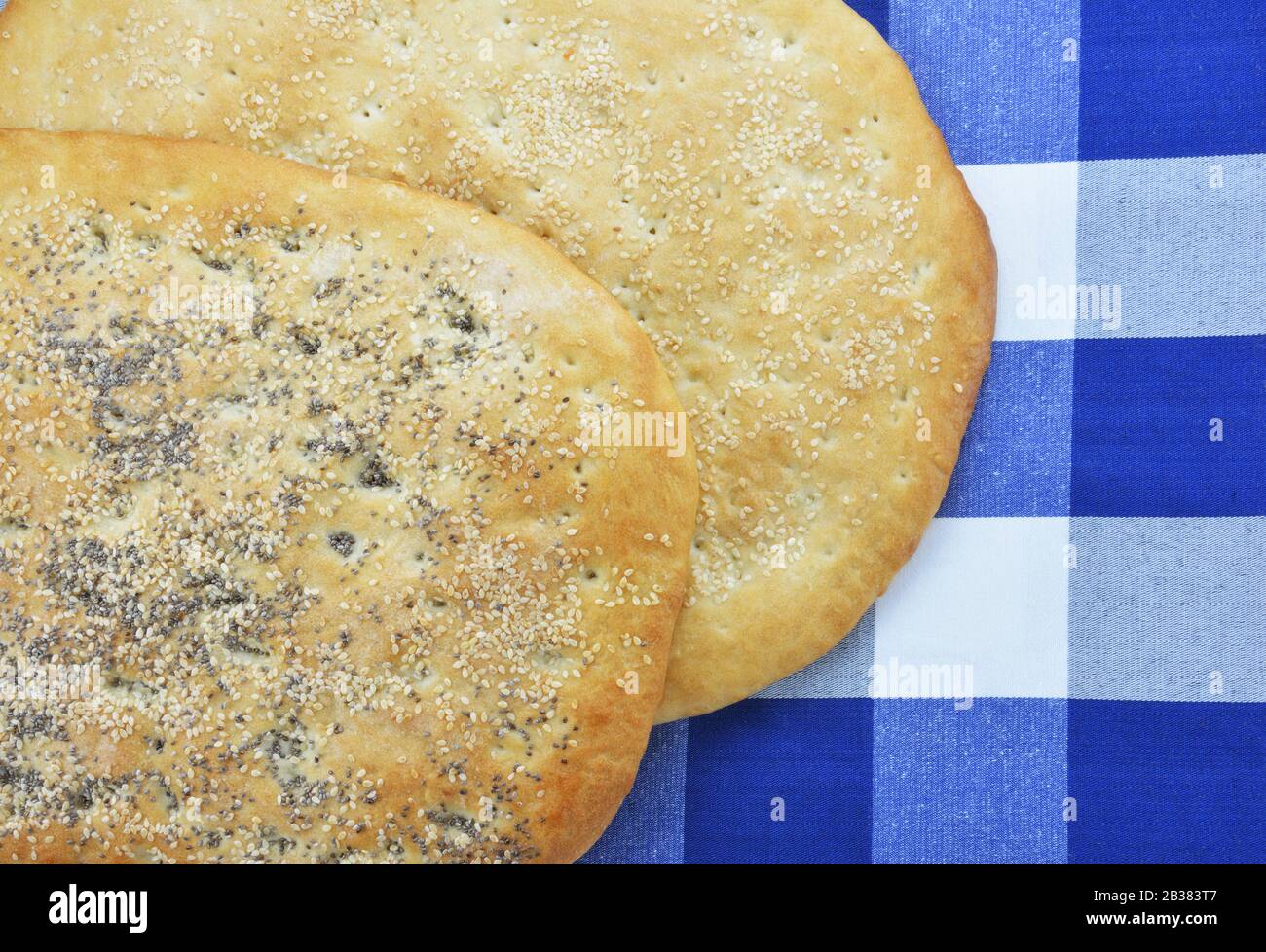Greek sesame flatbreads on checked tablecloth Stock Photo