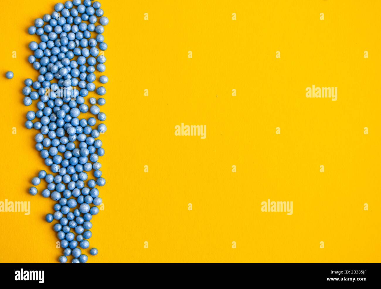 Colorful sprinkles in blue on yellow background with copy space for