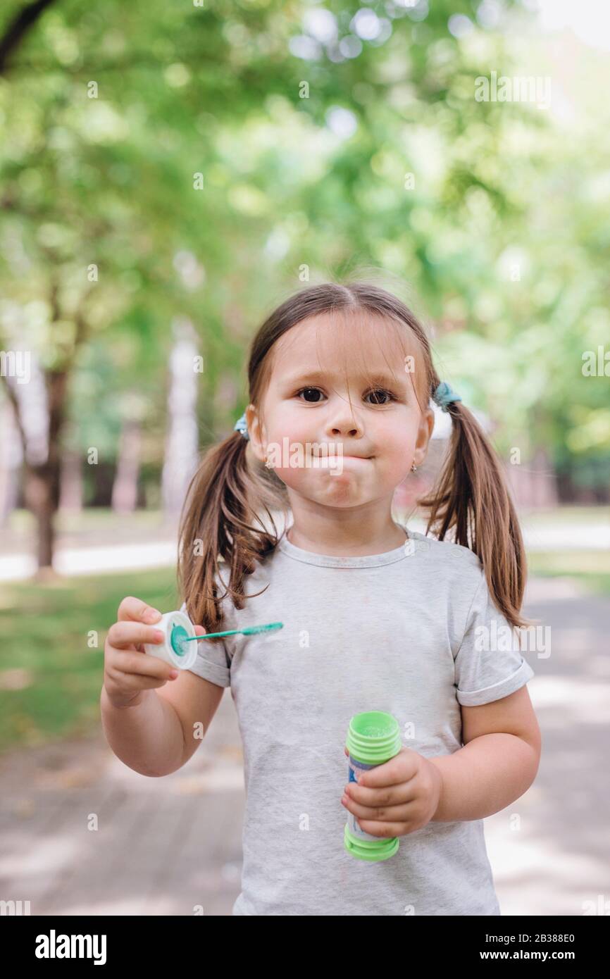 Cute little girl with a soap bubbles in park Stock Photo - Alamy