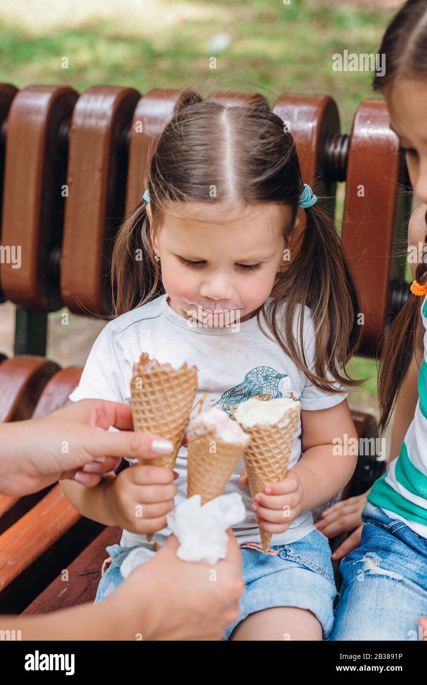 Close up of little cute girl looking at three icecream in her hands Stock Photo