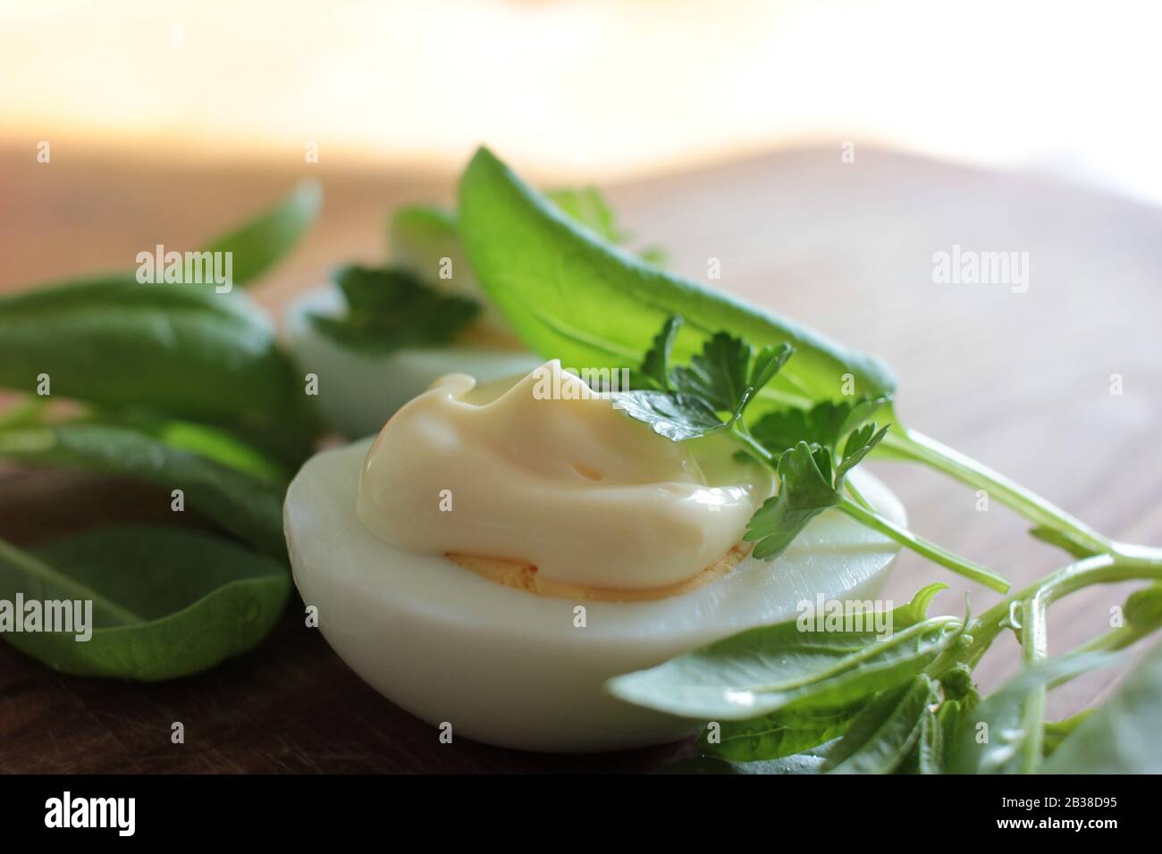 Boiled eggs with fresh baby leaf spinach and parsley on the wooden cutboard. Quick and easy spring breakfast recipe. Copy space Stock Photo