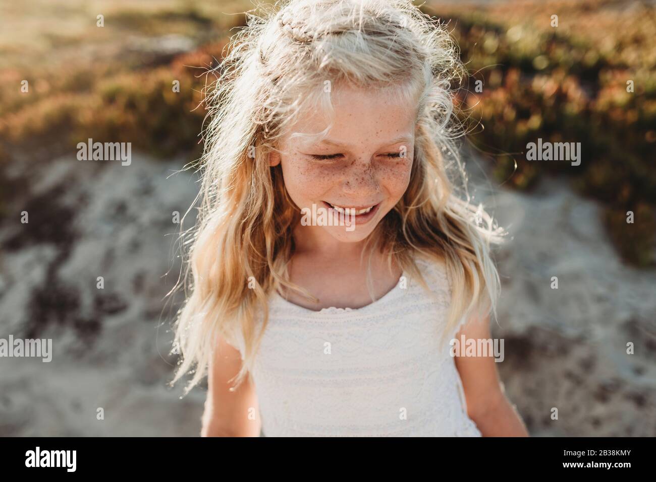 Portrait of young school age girl with freckles looking away on beach ...