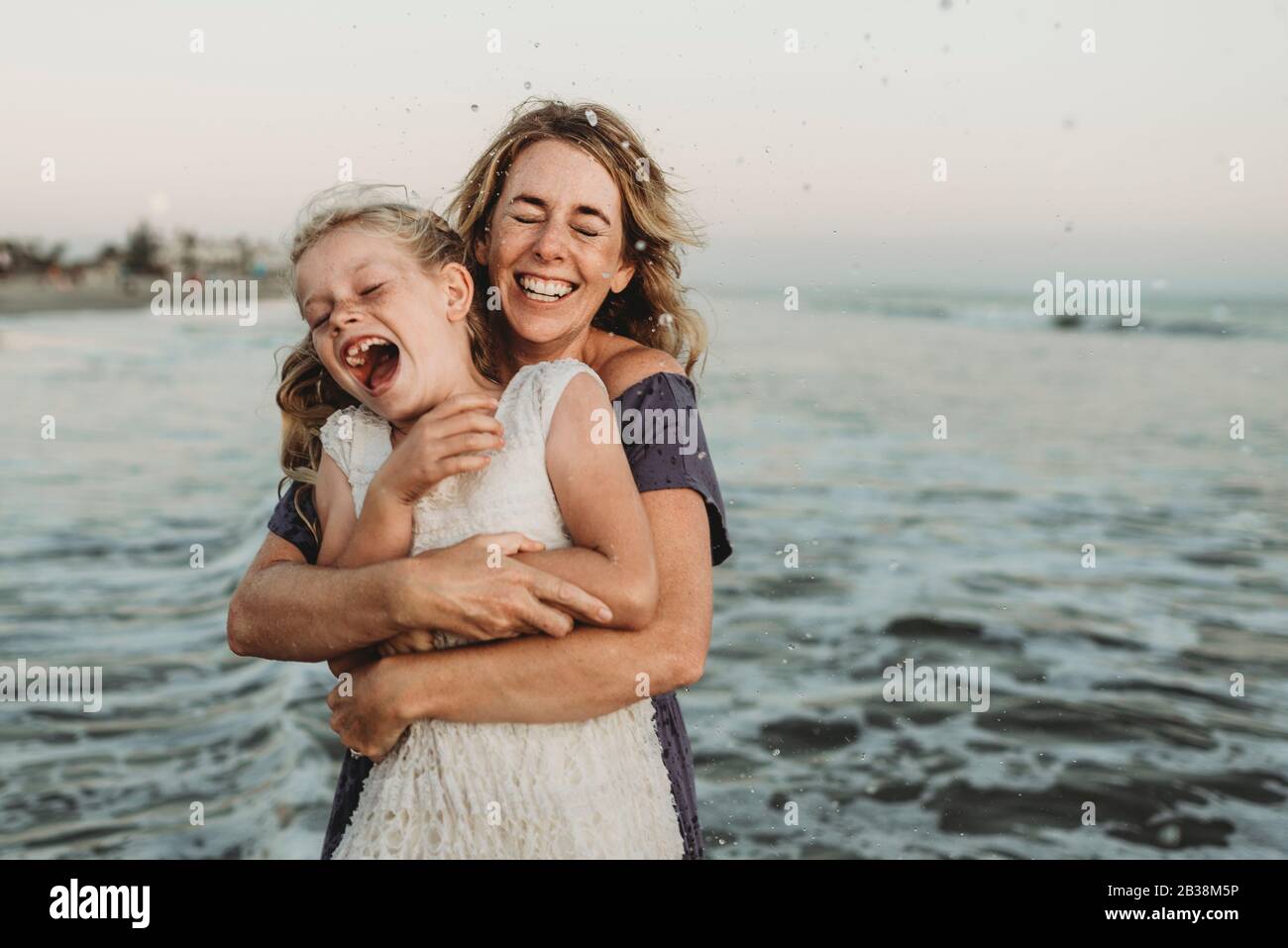 Mother embracing young girl with freckles in ocean Stock Photo
