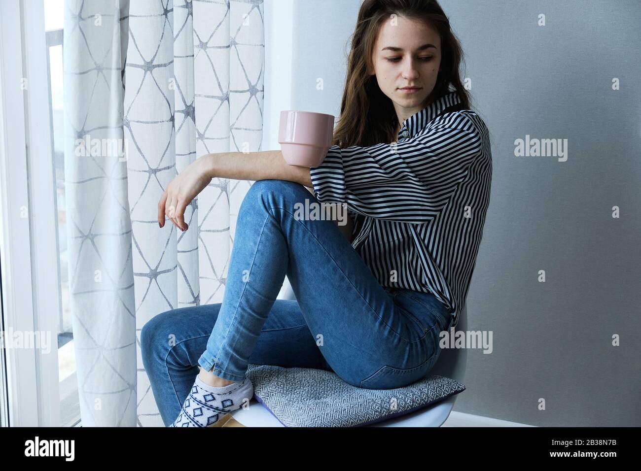 millennial brown-haired girl drinking tea with cakes alone Stock Photo