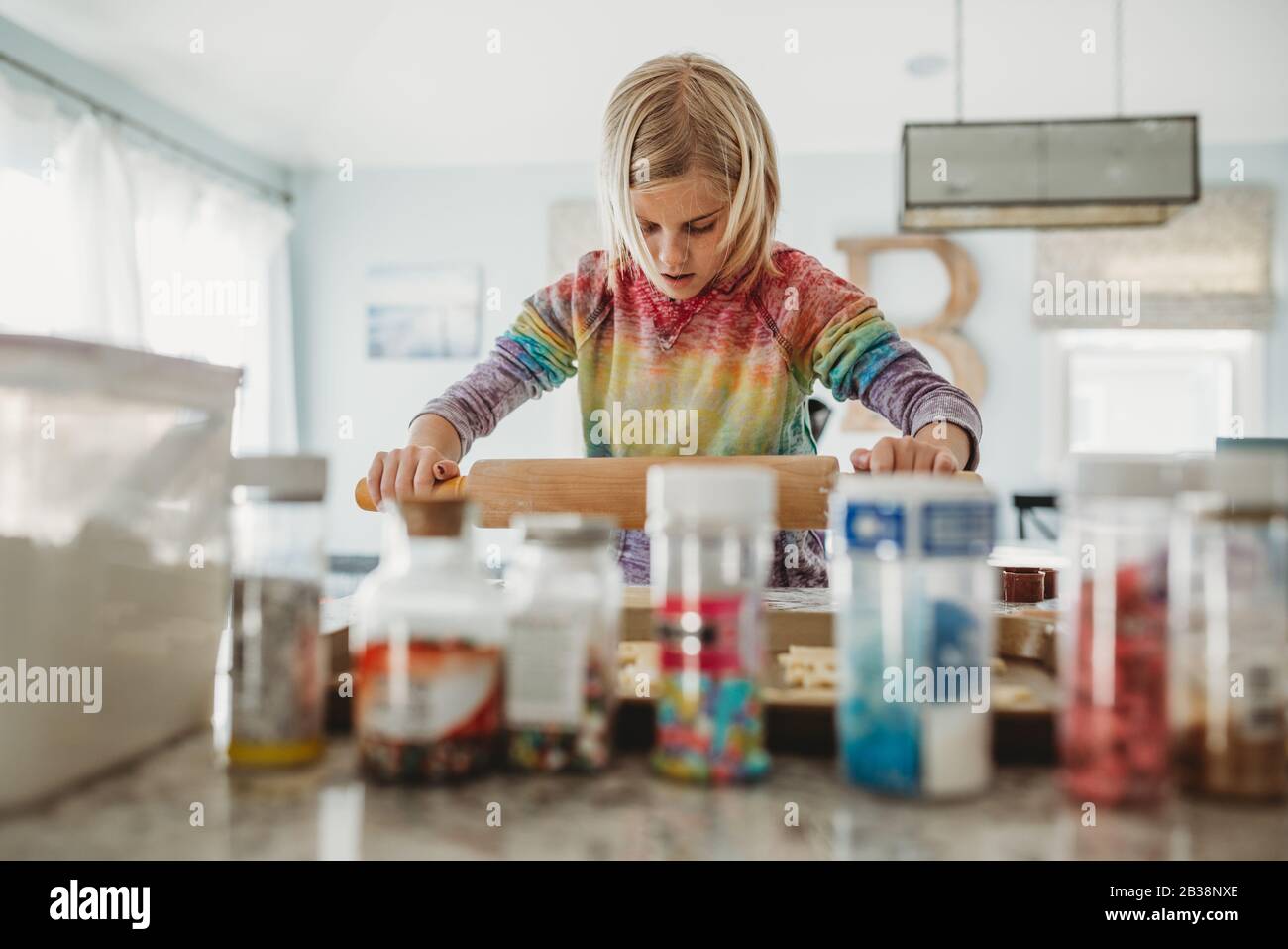 Young girl using a rolling pin to bake cookies in the kitchen Stock Photo