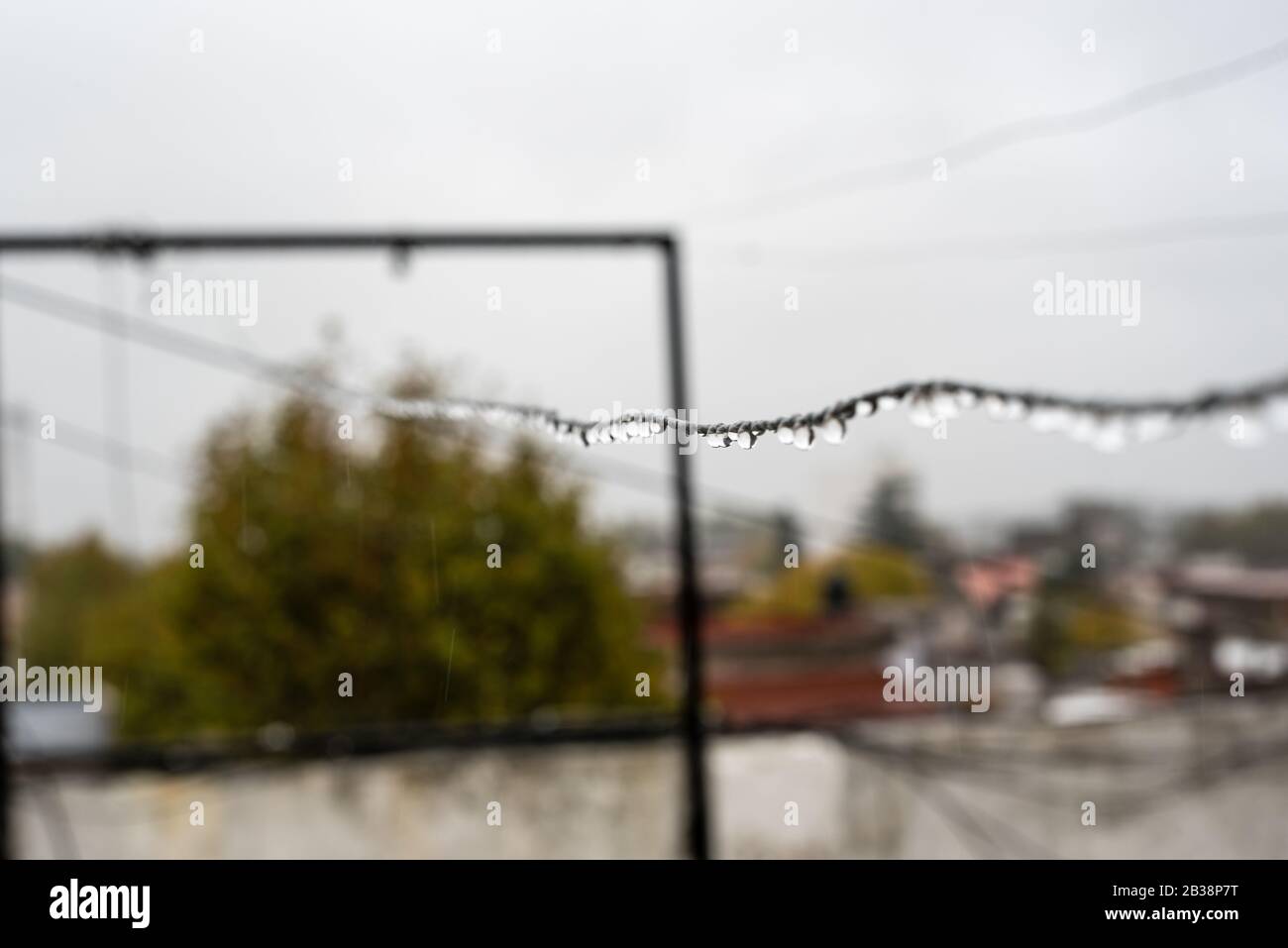 Clothesline wire full of small drops on a rainy day with a selective focus in the center very shallow depth of field Stock Photo