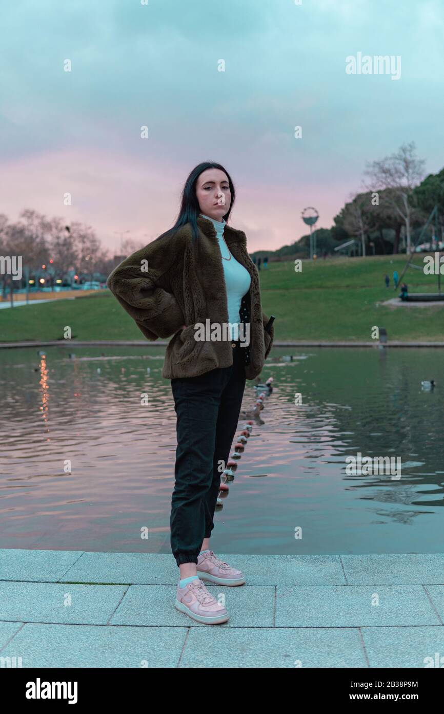 Retrato de joven de pie con abrigo y cielo rosado de atardecer Stock Photo