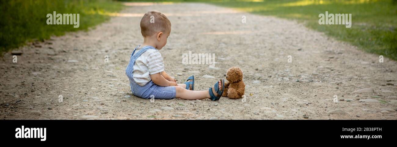 Little boy playing with teddy bear on the footpath Stock Photo - Alamy