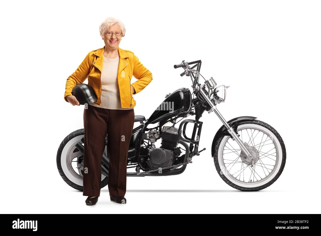 Full length portrait of a mature woman holding a helmet and standing next to a custom chopper motorcycle isolated on white background Stock Photo