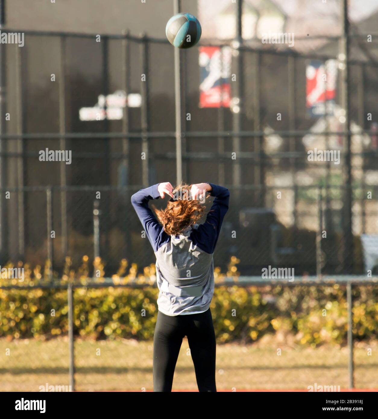 Female high school track and field athlete throwing a medicine ball backwards Stock Photo