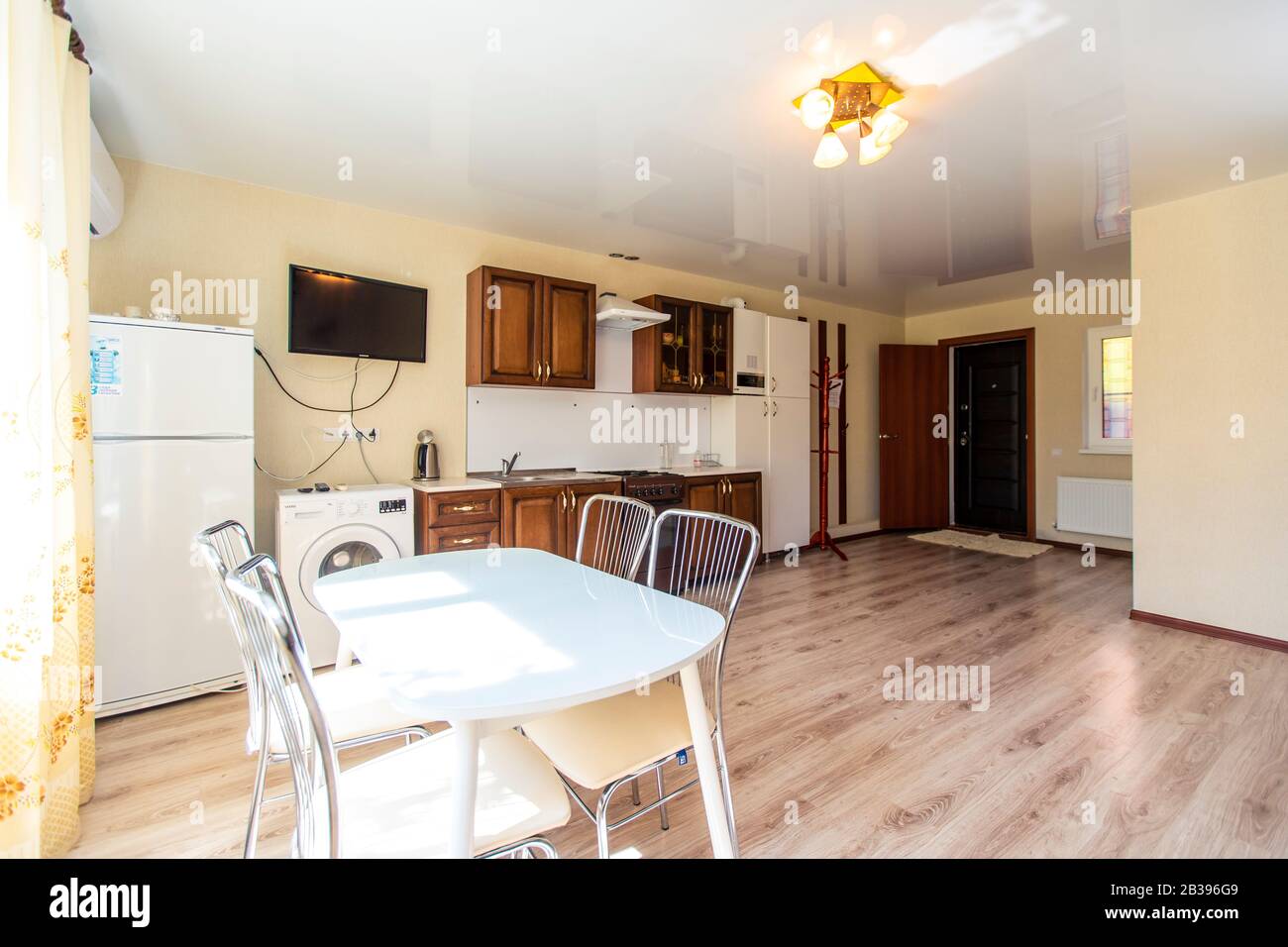 the kitchen is on the ground floor of the guest house. In the foreground is a white table with four chairs. Wooden kitchen furniture at the back. Frid Stock Photo