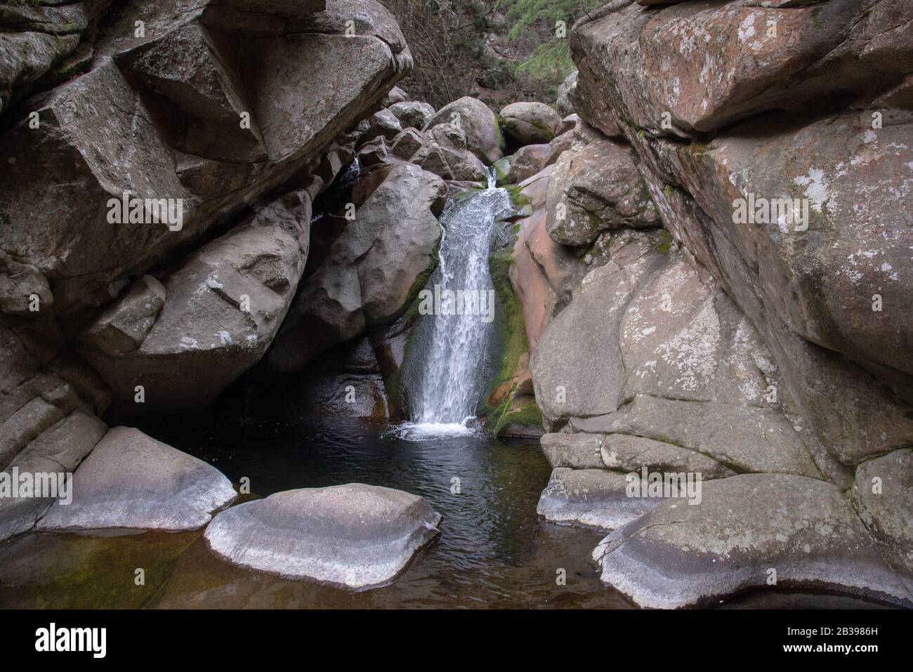 Wide view of a little waterfall in the middle of massive rocks Stock Photo