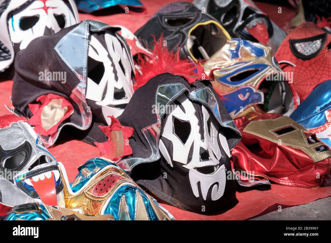 selection of Masks of mexican wrestlers on offer for sale on the ground in city market Stock Photo