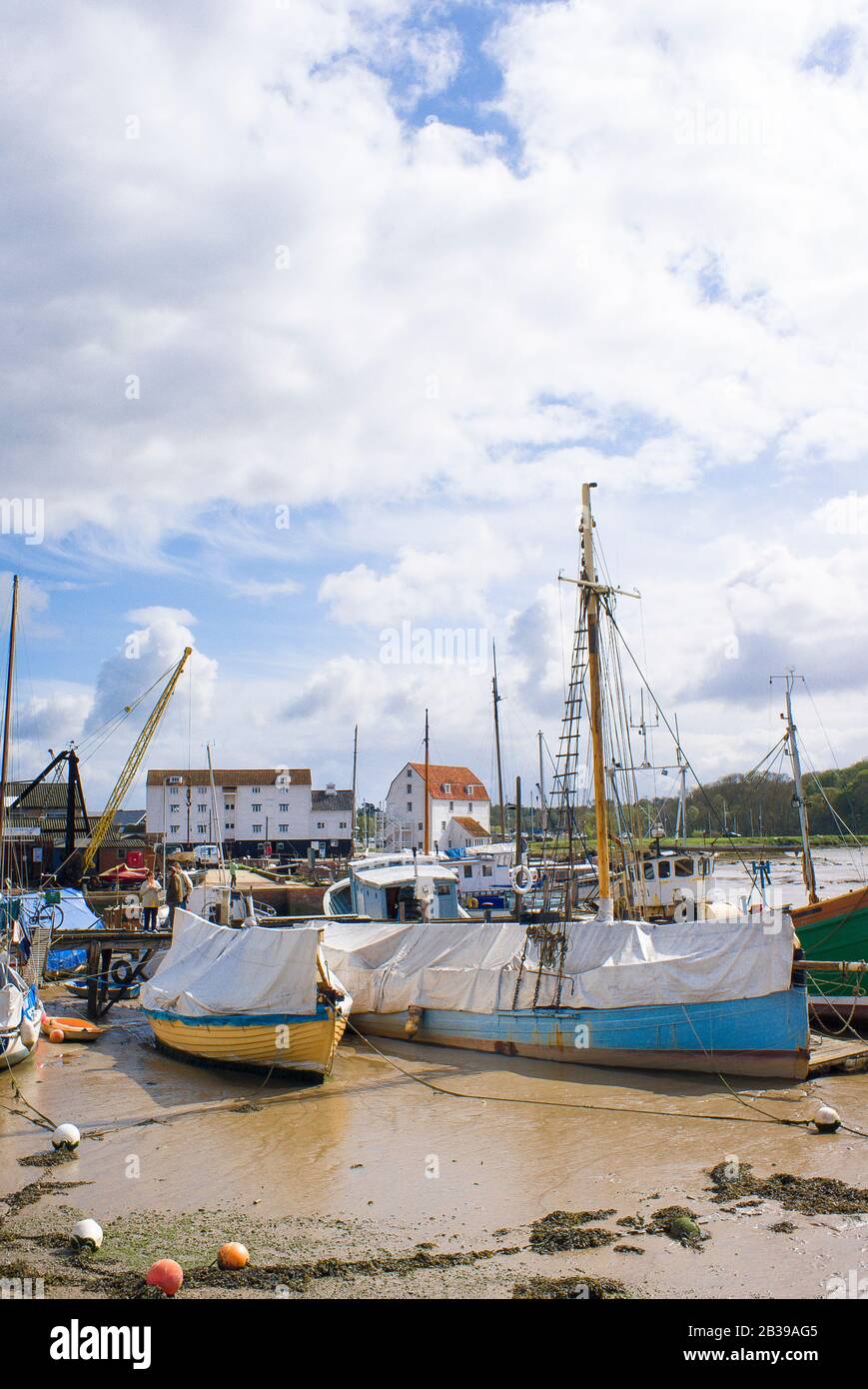 Low tide leaves small boats stranded in Woodbridge harbour on the River Deben in Suffolk England UK Stock Photo
