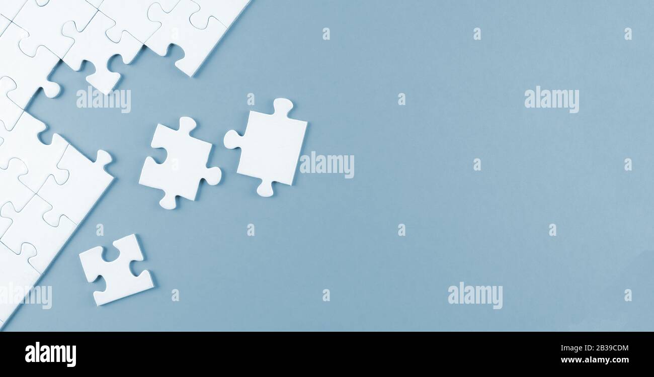 top view of white blank unfinished jigsaw puzzle on blue background, completing a task or solving a problem concept Stock Photo