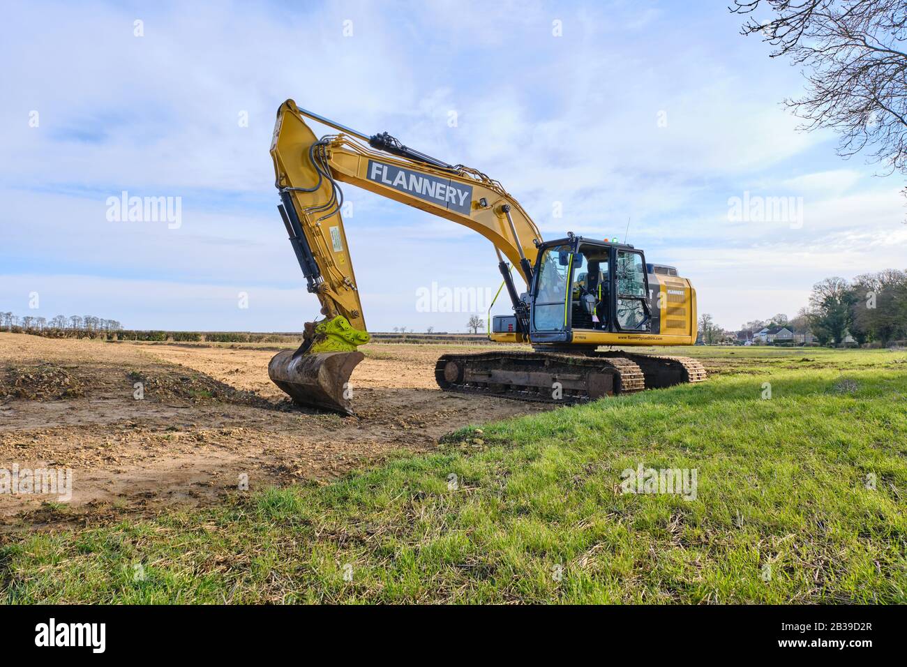 A large CAT 360 tracked Excavator operated by Flannery plant hire in a Lincolnshire field carrying out groundworks prior to water main laying Stock Photo