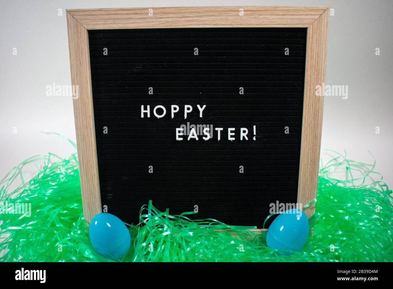 A Black Happy Easter Sign With White Letters, Easter Grass, and Easter Eggs Stock Photo