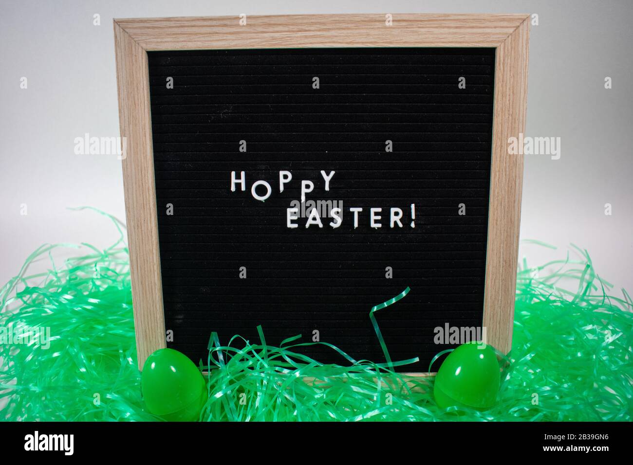 A Black Happy Easter Sign With White Letters, Easter Grass, and Easter Eggs Stock Photo