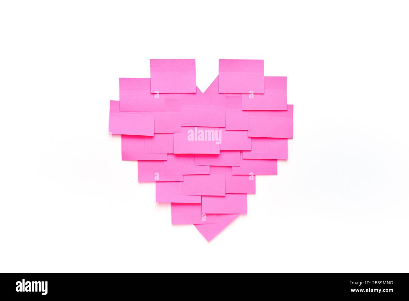 Blank pink sticky notes stick to white wall in heart shape. Valentine
