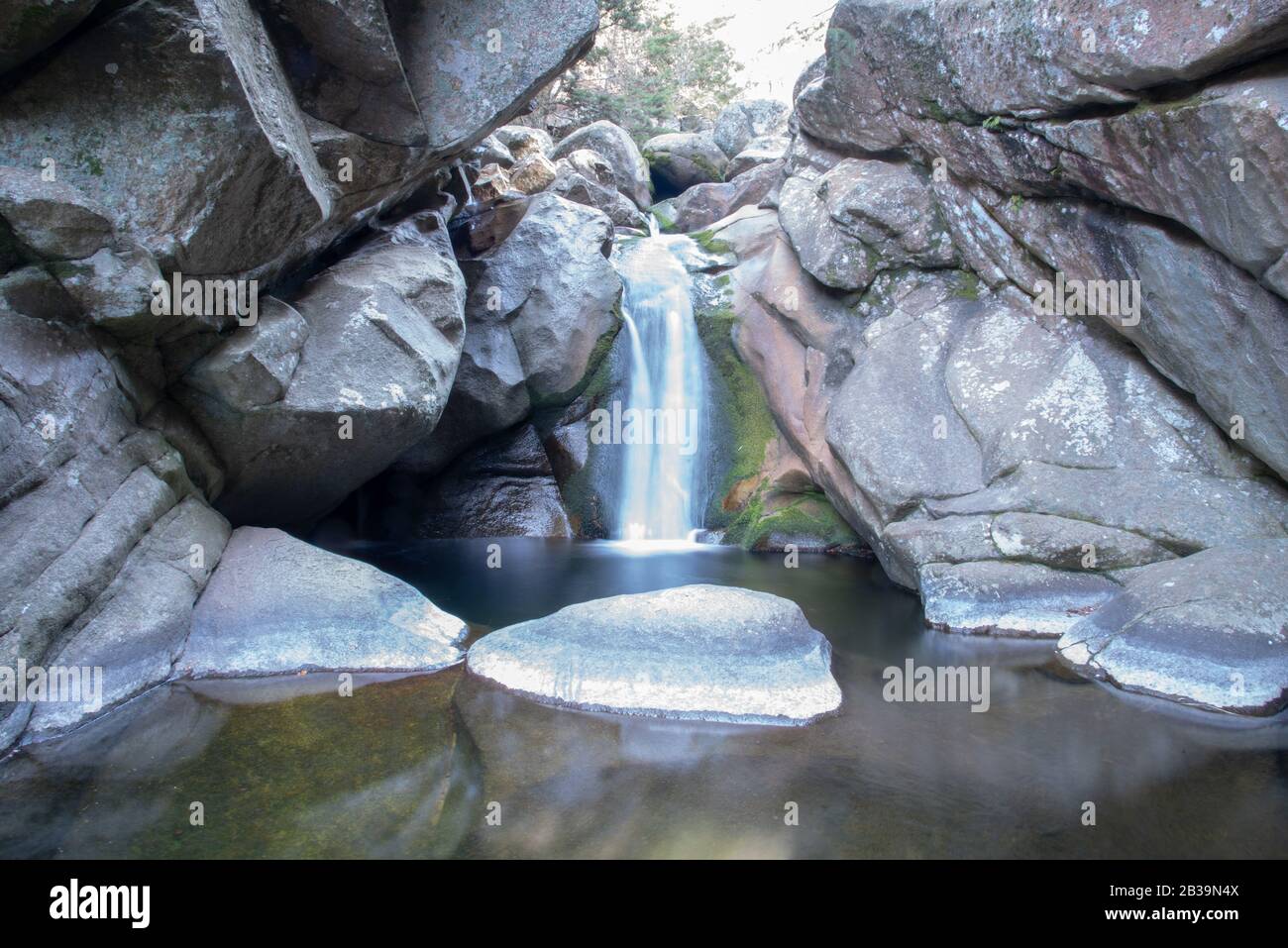 View of a little waterfall in the middle of massive rocks Stock Photo