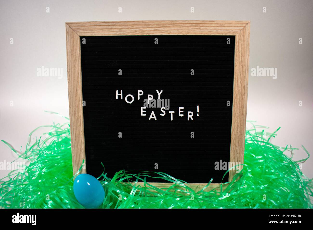 A Black Happy Easter Sign With White Letters, Easter Grass, and Easter Eggs Stock Photo