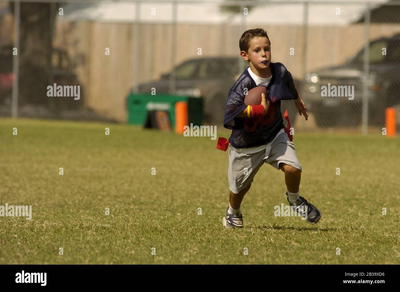 Austin Texas USA, October 2004: Eight-year-old boy wearing a plastic mouth guard runs downfield during a youth league flag football game. ©Bob Daemmrich Stock Photo