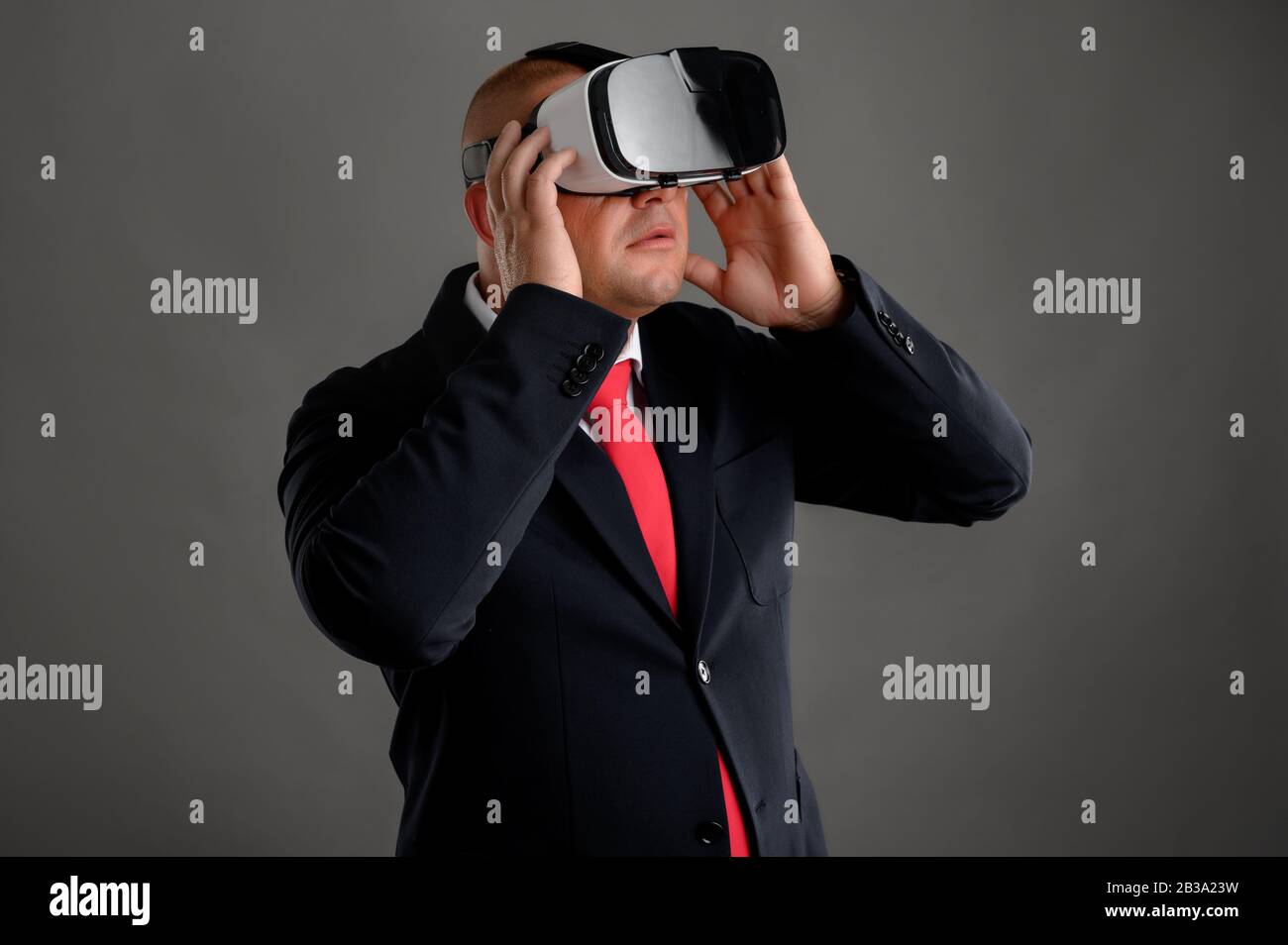 Businessman dressed in black suit wearing virtual reality VR glasses ...