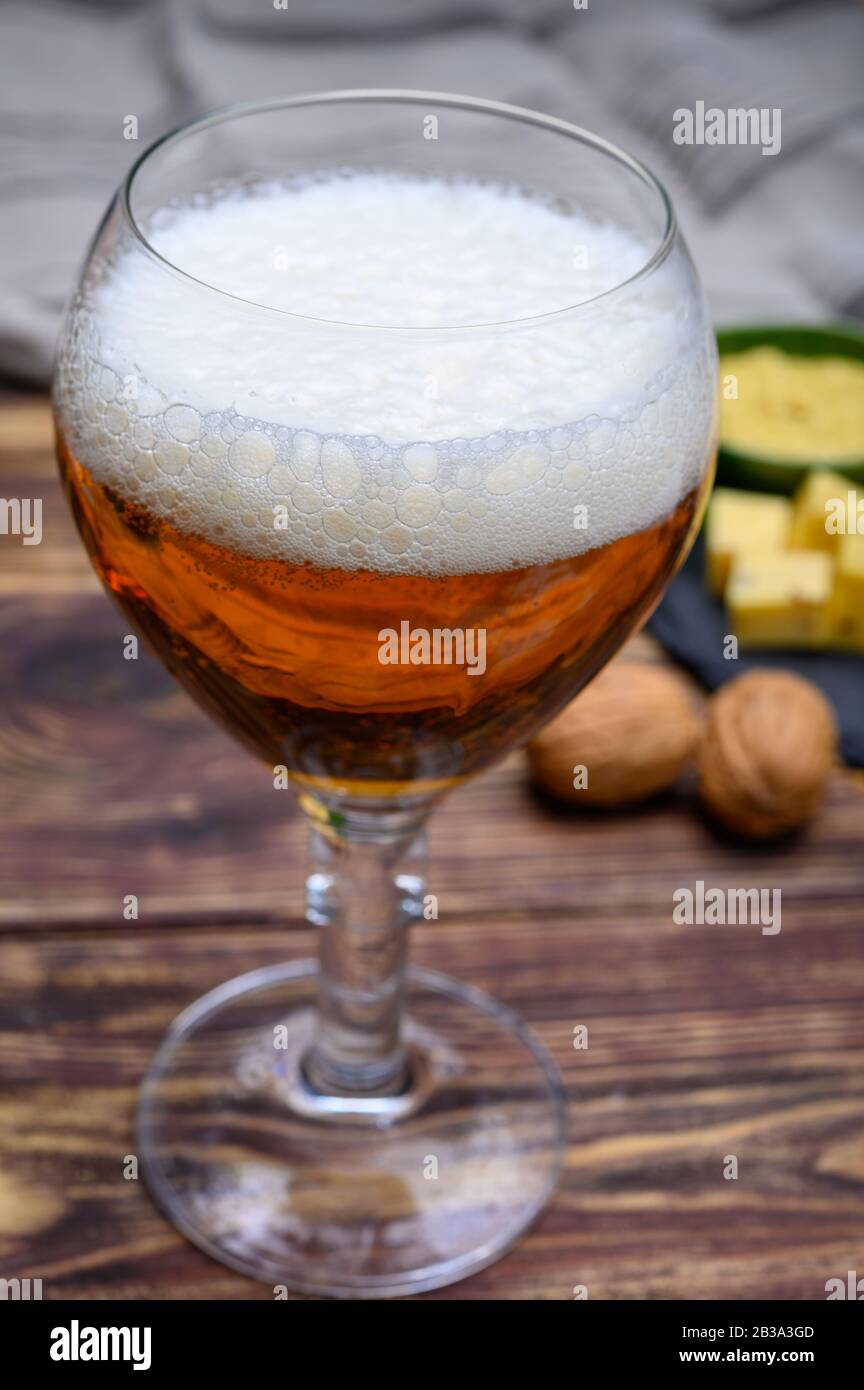 Glass of Belgian abbey blond beer and stone plate with cheeses made by