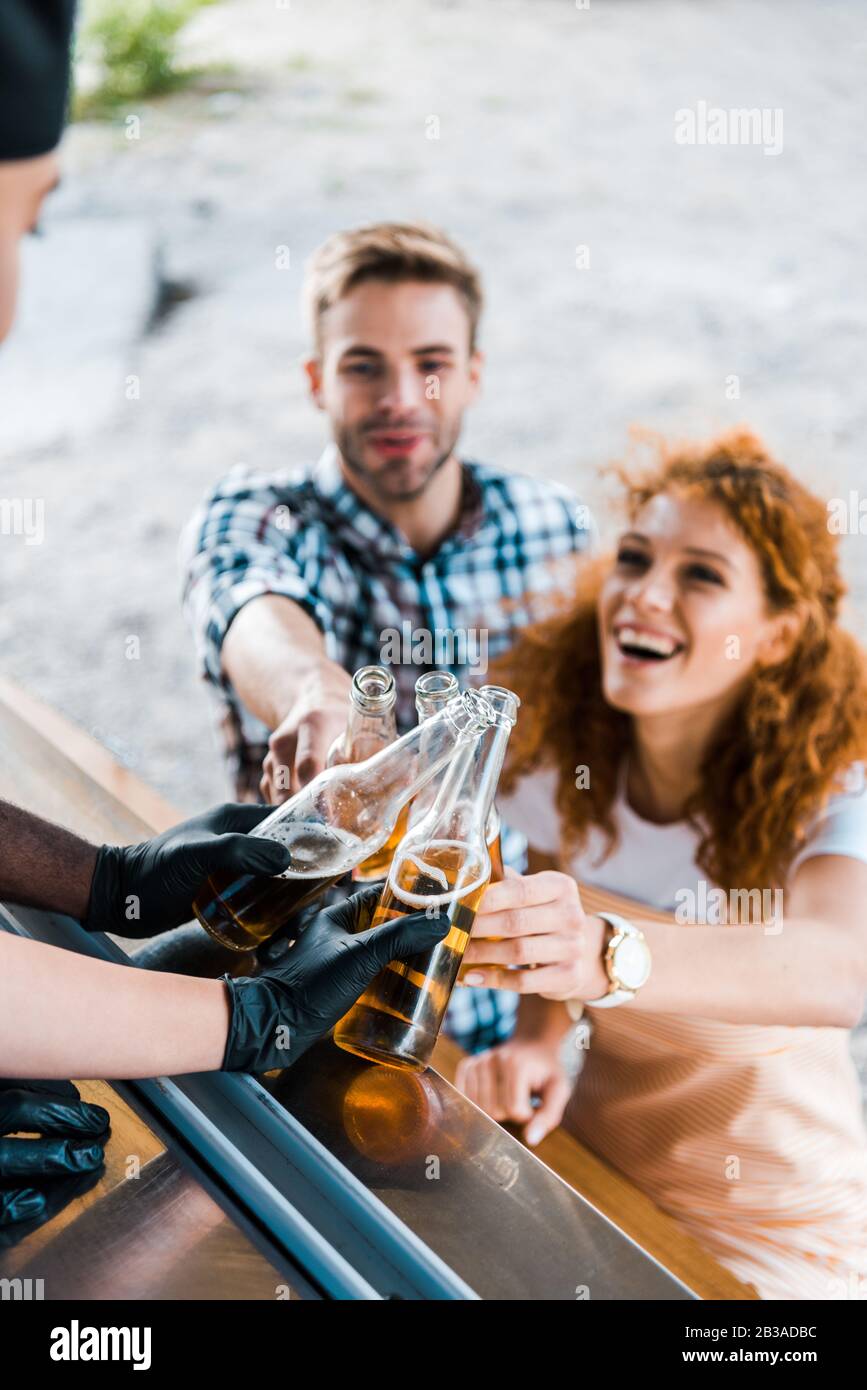selective focus of multicultural chefs toasting with bottles of beer near customers Stock Photo