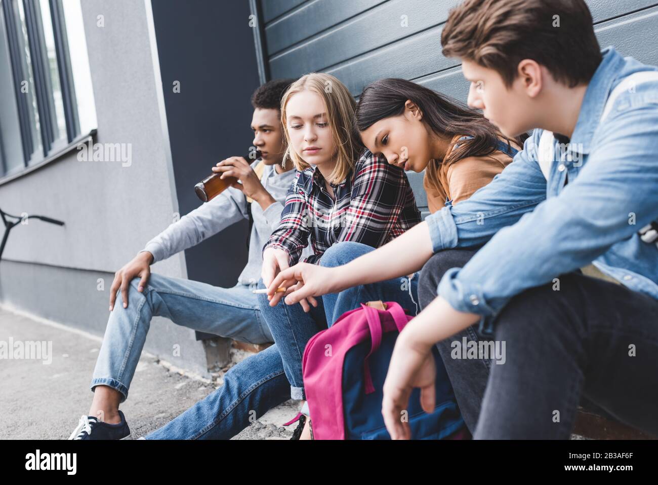 teenagers sitting, drinking beer from glass bottle and smoking ...