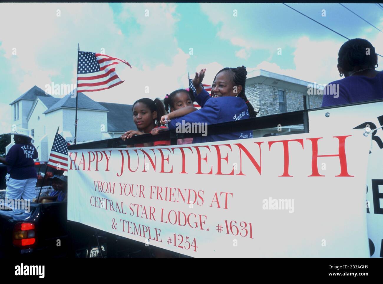 Austin, Texas USA,19 JUN 2002: Black children and woman wave to spectators lining the street as they ride on a float in the annual Juneteenth parade through the streets of historically black east Austin. ©Bob Daemmrich Stock Photo