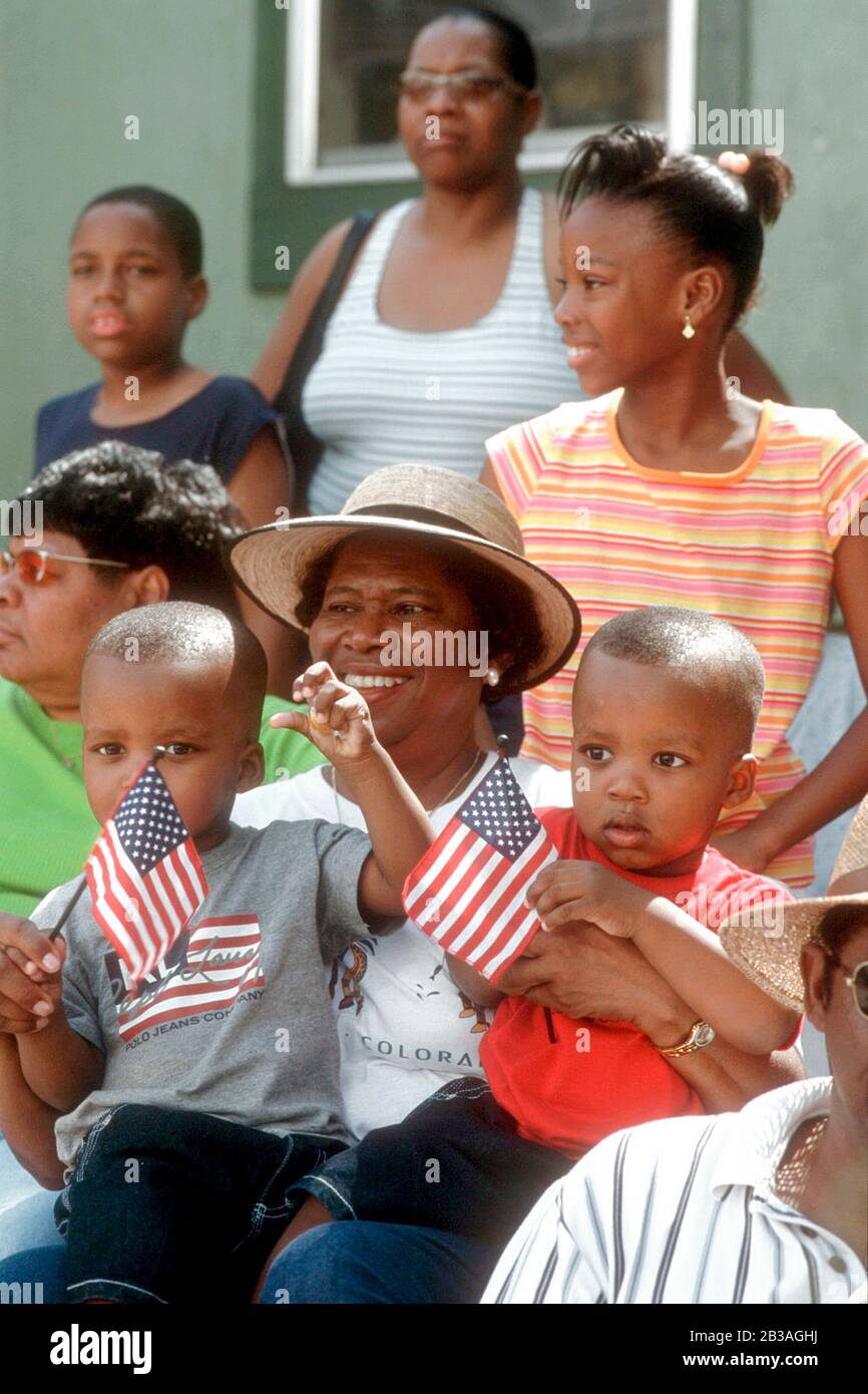 Austin, Texas USA, June 19, 2002:: Black woman wearing hat holds two little boys waving American flags as they watch Austin's annual Juneteenth parade through the streets of historically black east Austin. © Bob Daemmrich Stock Photo