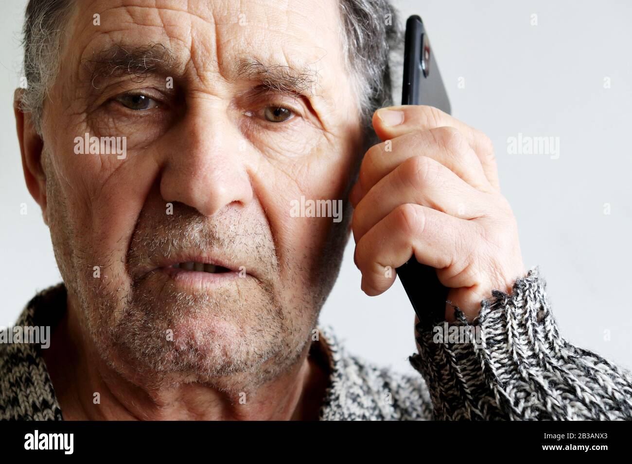 Portrait of unshaven elderly man talking on mobile phone, smartphone in male hands close up. Concept of communication in retirement Stock Photo