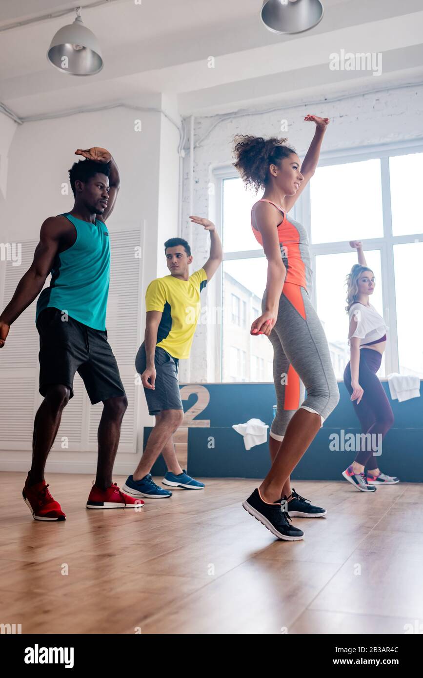 Side view of young multicultural dancers with hands in air dancing ...
