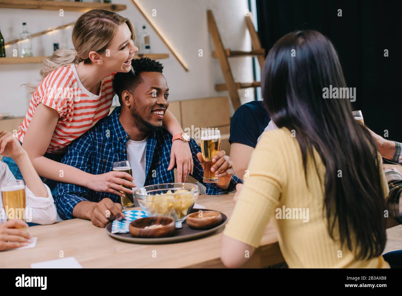 young woman hugging african american man near multicultural friends in ...
