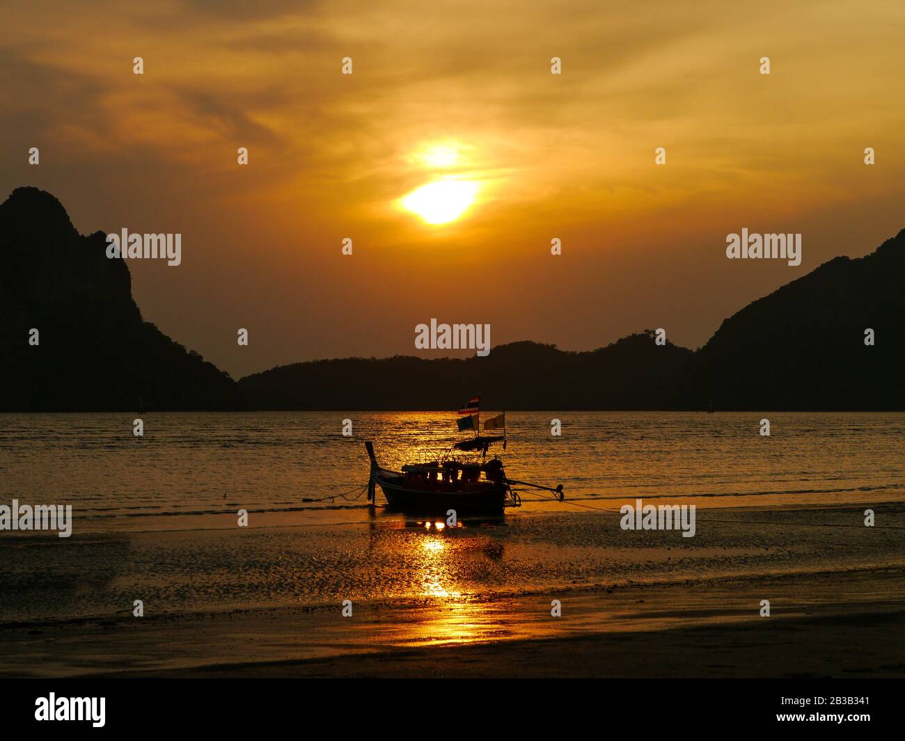 Sensational golden sunset over the beautiful Pak Meng beach with a traditional Thai Long-tail boat Stock Photo