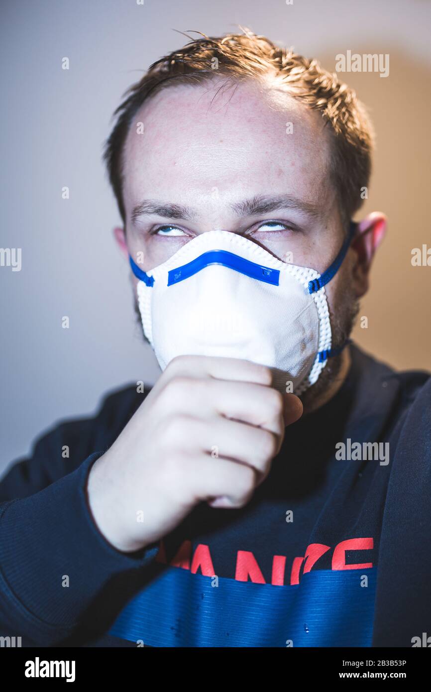 Man with real Coronavirus COVID-19 disease symptoms wears a protective mask Stock Photo