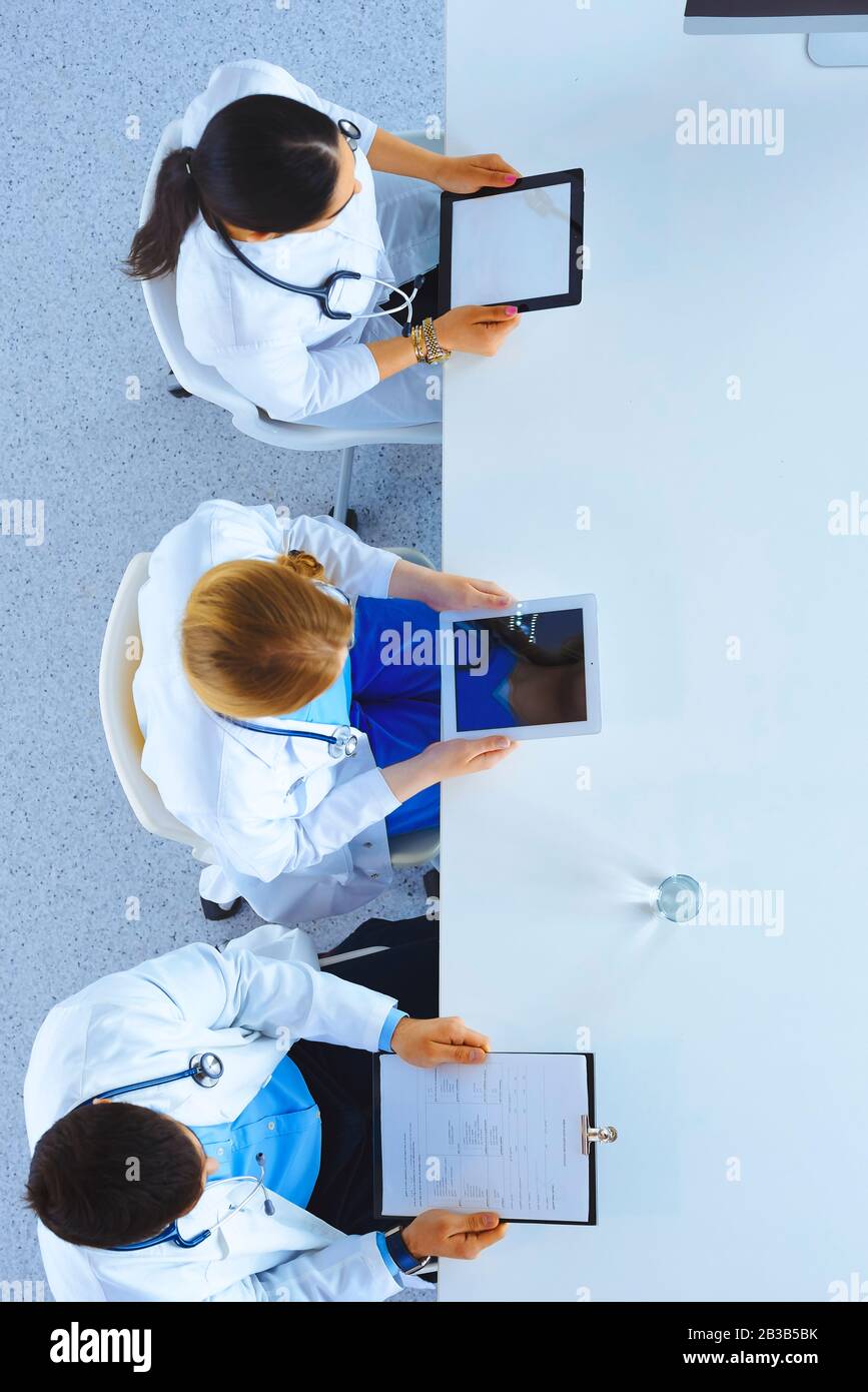 Group of doctors sitting in he office with gadgets and tablets in ...