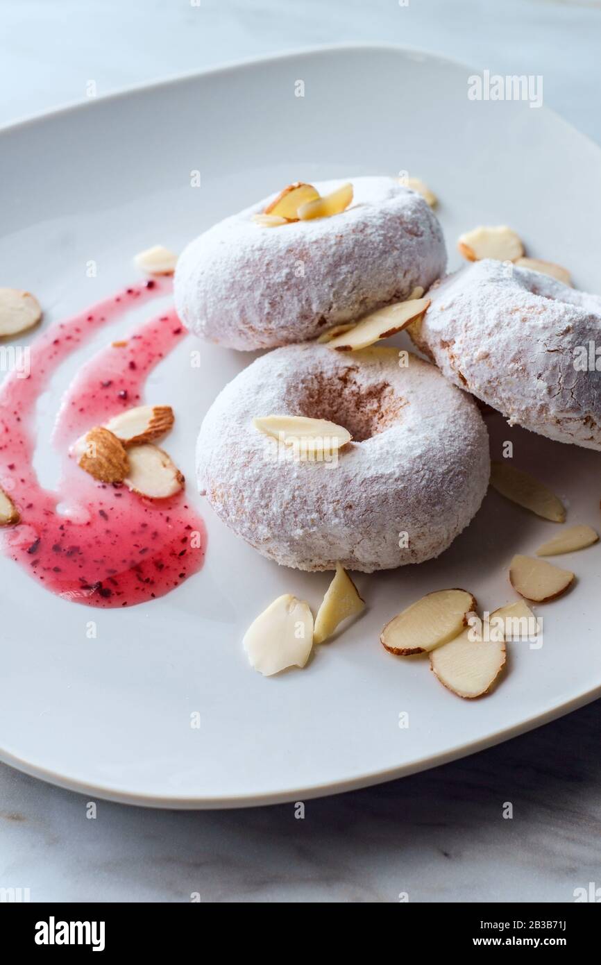 Powdered sugar cake doughnuts with holes served with raspberry jam and slivered almonds Stock Photo