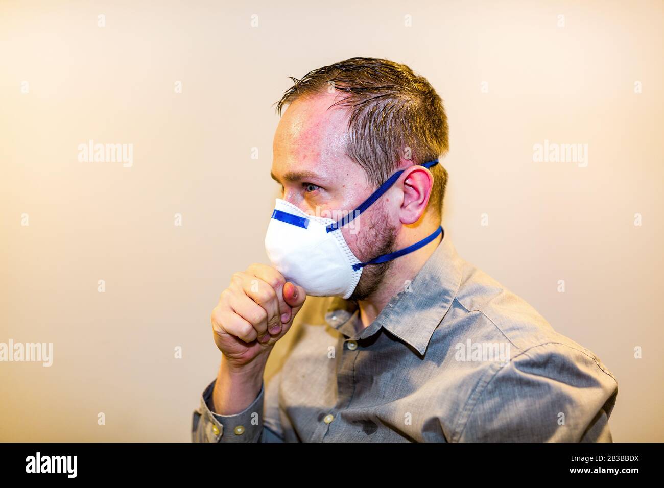 Man with real Coronavirus COVID-19 disease symptoms wears a protective mask Stock Photo